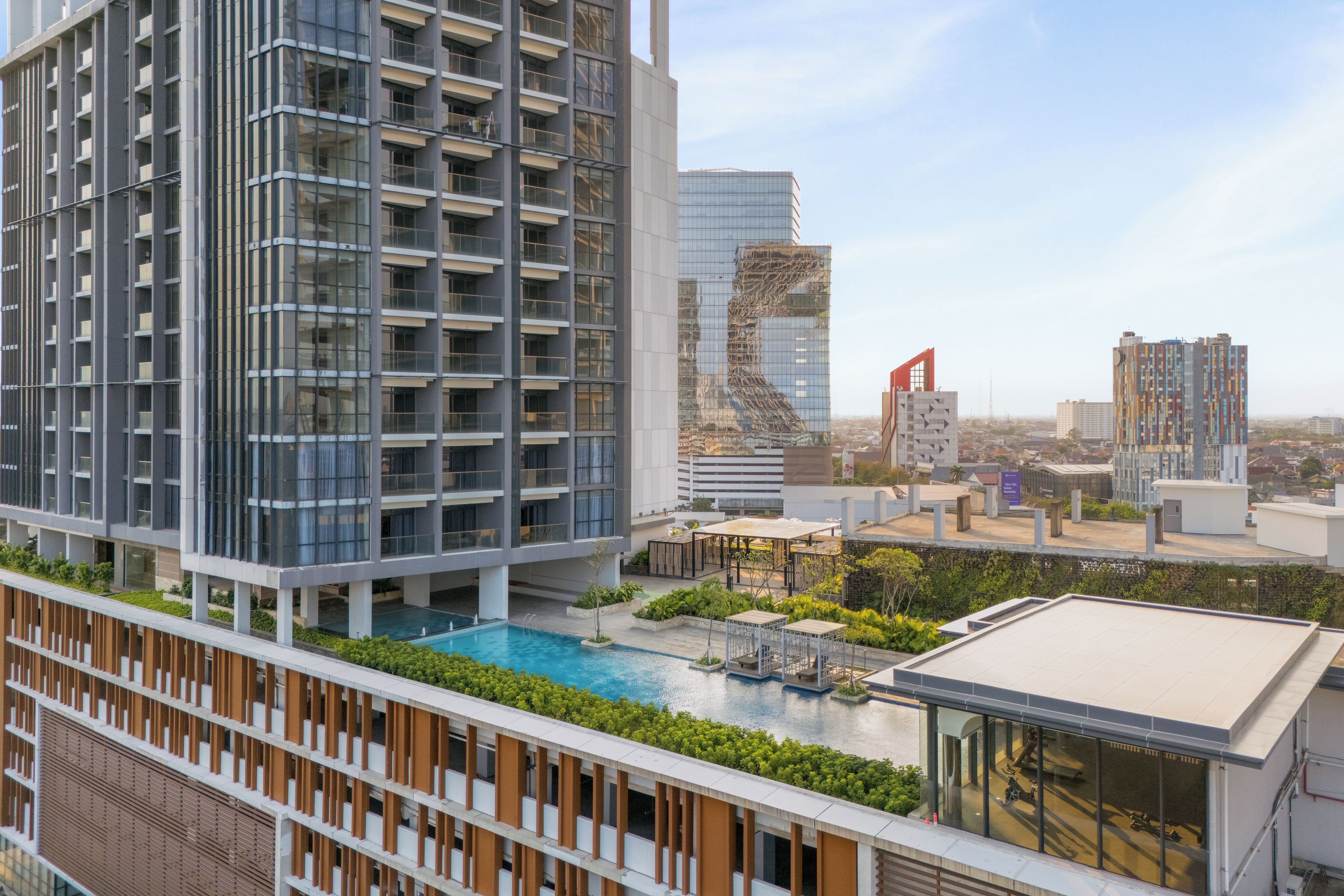A modern high-rise building with a rooftop pool and outdoor seating area.
