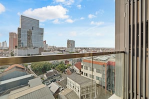 A high-rise building with a view of a cityscape, including various other buildings and a clear sky.