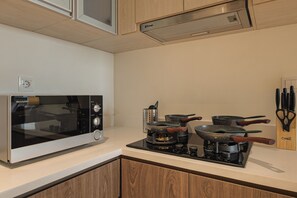 Cozinha equipada com micro-ondas, fogão e panelas.