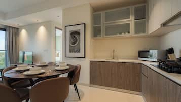 A modern kitchen with a dining area, featuring a round table with chairs, a built-in oven, and a microwave.