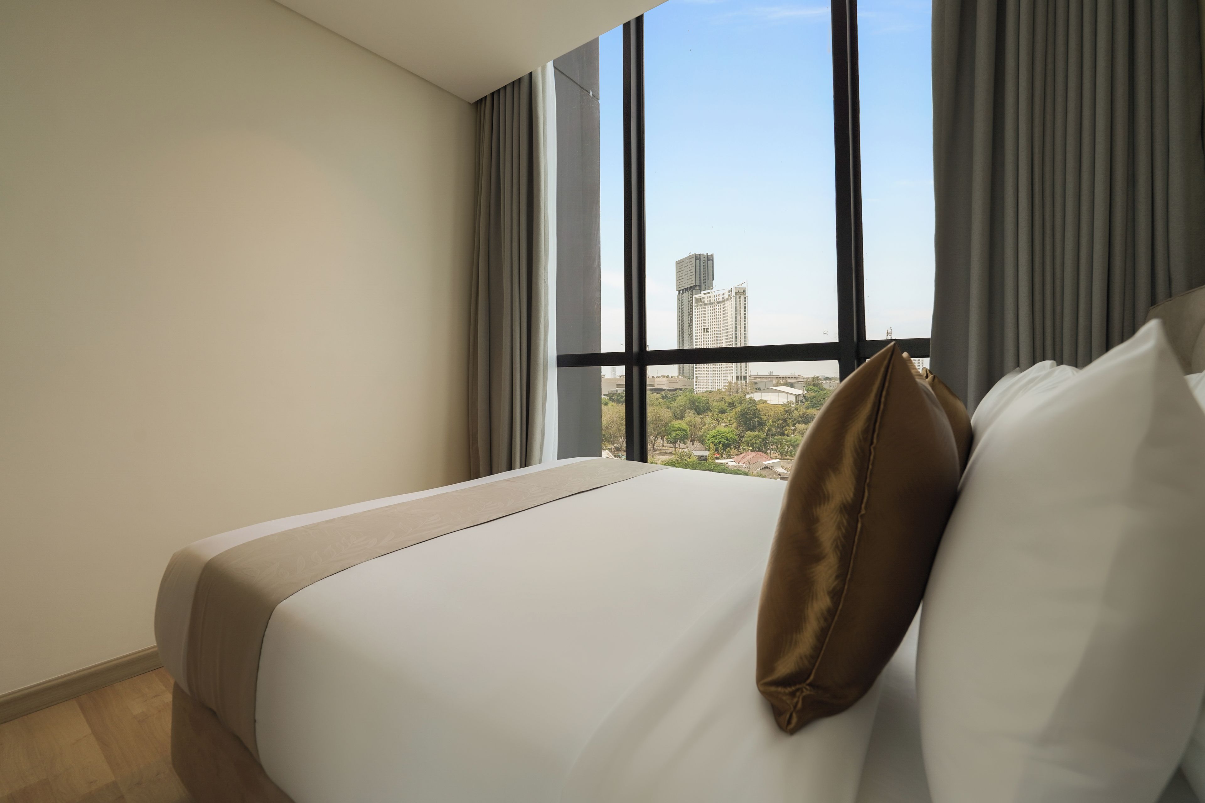 Una camera d'albergo con un letto grande, vista sulla città dalla finestra e una tenda.