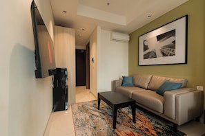 A modern living room with a sofa, a coffee table, and a flat-screen TV mounted on the wall.