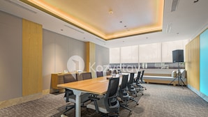 A modern conference room with a long table, chairs, and a large window.