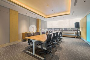 A modern conference room with a long table, chairs, and a large window.