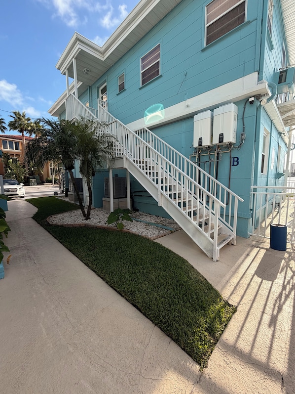 A two-story building with a white staircase and a small garden area. - Waterfront Studio Clearwater Beach+Pool (Clearwater)
