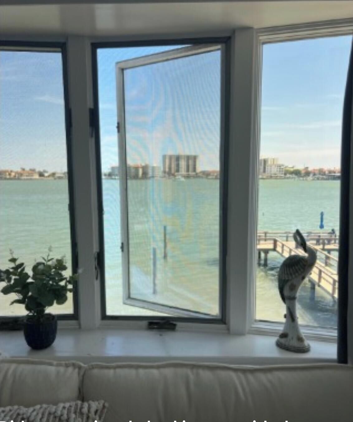 A room with a large window overlooking a body of water and a cityscape.