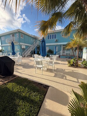 A blue building with outdoor seating, palm trees, and a clear sky. - Waterfront Studio Clearwater Beach+Pool (Clearwater)