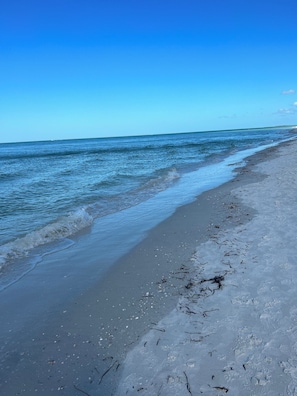 Ein Strand mit blauem Himmel und ruhigem Meer.