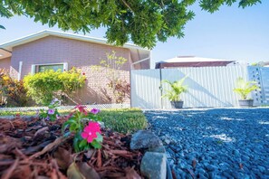 A residential area with a house, a white fence, and a gravel driveway. - BayNest Cozy South Miami Suite Long Stay Friendly (Cutler Bay)