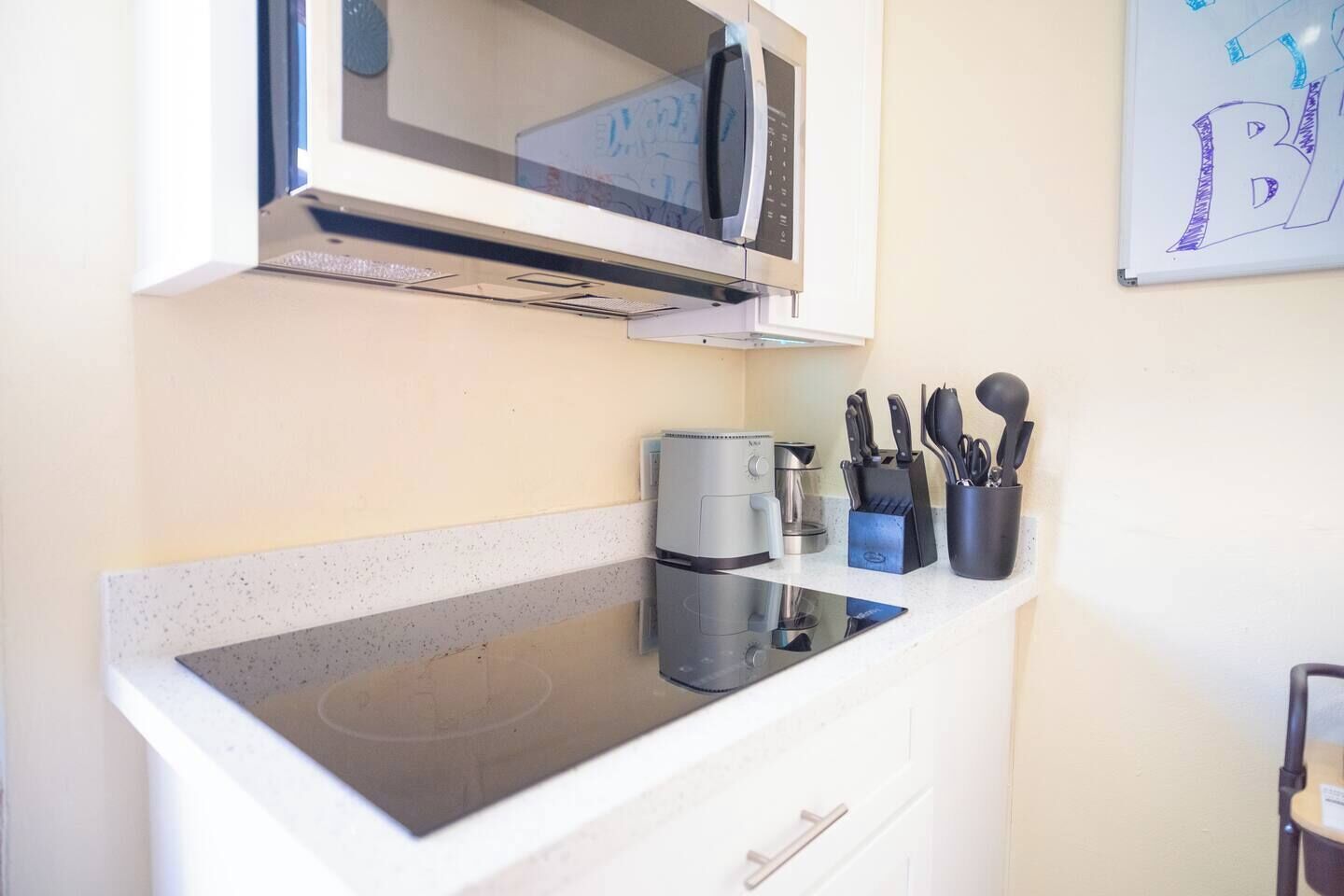 A kitchenette with a microwave, coffee maker, and knife block.