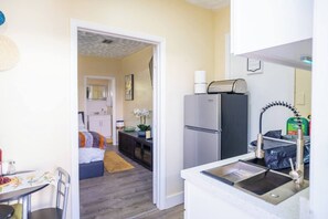A compact kitchen with a refrigerator, sink, and a small dining area with a table and chairs. - BayNest Cozy South Miami Suite Long Stay Friendly (Cutler Bay)