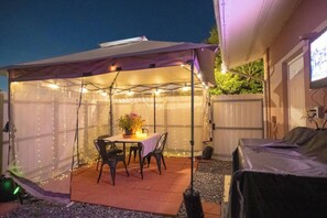 A covered patio area with a table and chairs, surrounded by string lights. - BayNest Cozy South Miami Suite Long Stay Friendly (Cutler Bay)