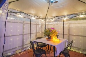 A tented outdoor area with a table set for dining, chairs, a ceiling fan, and string lights. - BayNest Cozy South Miami Suite Long Stay Friendly (Cutler Bay)