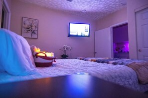 A bedroom with a bed, a television mounted on the wall, a nightstand, and a door leading to another room. - BayNest Cozy South Miami Suite Long Stay Friendly (Cutler Bay)