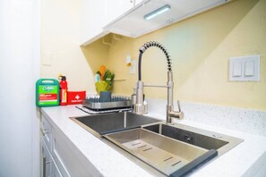 A kitchen with a stainless steel sink, a faucet, and a countertop. There are cleaning supplies on the counter. - BayNest Cozy South Miami Suite Long Stay Friendly (Cutler Bay)