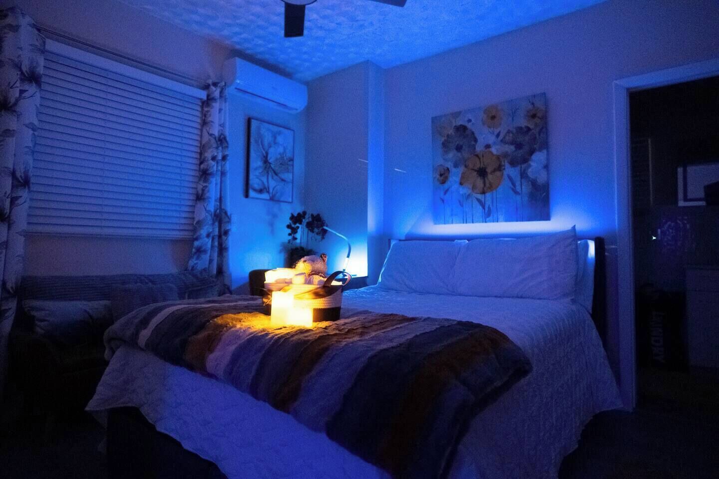 A bedroom with a bed, a bedside table, a lamp, and a wall painting.