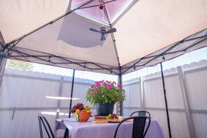A covered patio area with a table set for a meal, a potted plant, and a ceiling fan. - BayNest Cozy South Miami Suite Long Stay Friendly (Cutler Bay)
