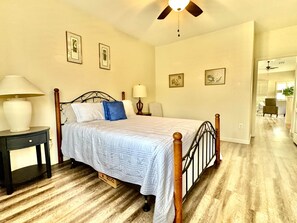 A bedroom with a bed, bedside tables, a ceiling fan, and a view into the adjacent living area. - Vistoso Village #70 (Oro Valley)