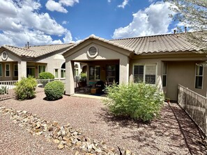 A two-story house with a covered porch, a fenced yard, and a gravel driveway. - Vistoso Village #70 (Oro Valley)