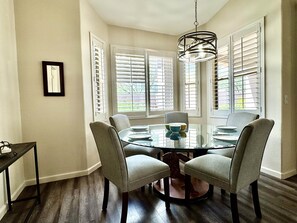 A dining area with a round glass table, four chairs, and a hanging light fixture. - Vistoso Village #70 (Oro Valley)