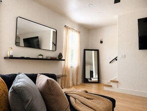 Ein modernes Wohnzimmer mit einer Couch, einem Couchtisch, einem Spiegel und einer Treppe.