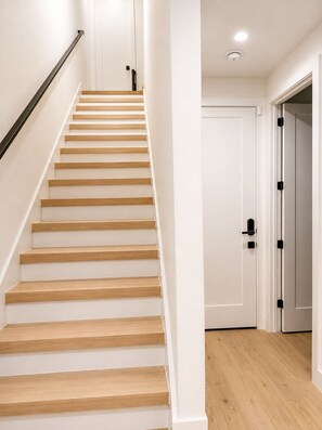 A staircase with wooden steps and a black handrail leading to a white door. - Modern Retreat Near Bishop Arts + Downtown Dallas (Dallas)