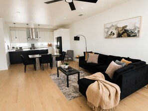 A modern living space with a dining area, a black sofa, and a kitchen in the background. - Modern Retreat Near Bishop Arts + Downtown Dallas (Dallas)