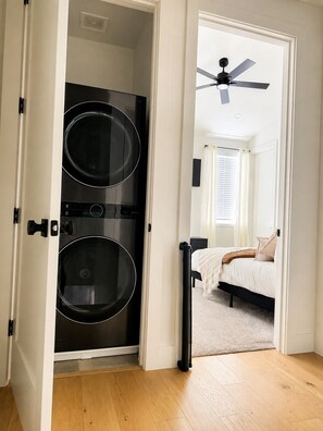 Une pièce comprenant un lit, un ventilateur de plafond et un espace buanderie avec deux machines à laver.