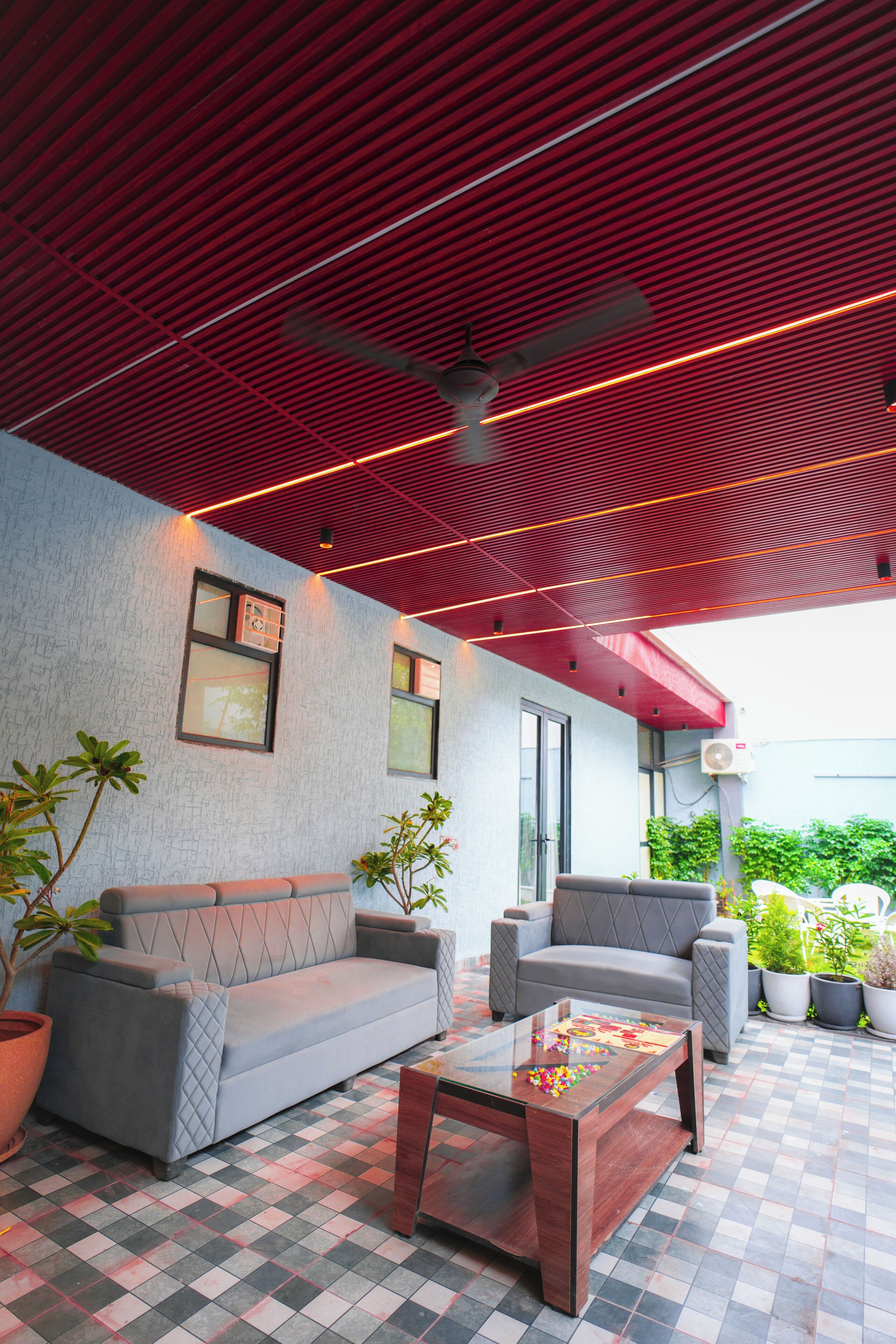 An outdoor seating area with a checkered floor, two sofas, a coffee table, and potted plants.