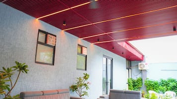 An outdoor seating area with a checkered floor, two sofas, a coffee table, and potted plants.