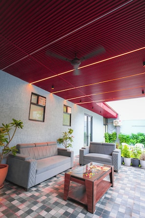 An outdoor seating area with a checkered floor, two sofas, a coffee table, and potted plants.
