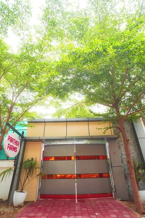A gated entrance with a sign reading 'PANTHER FARMS' and a red brick pathway leading to it. - Panther Farm Patrakar (Jaipur)