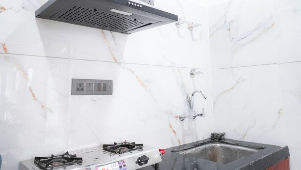 Una cocina con estufa a gas, campana extractora y baldosas de mármol.