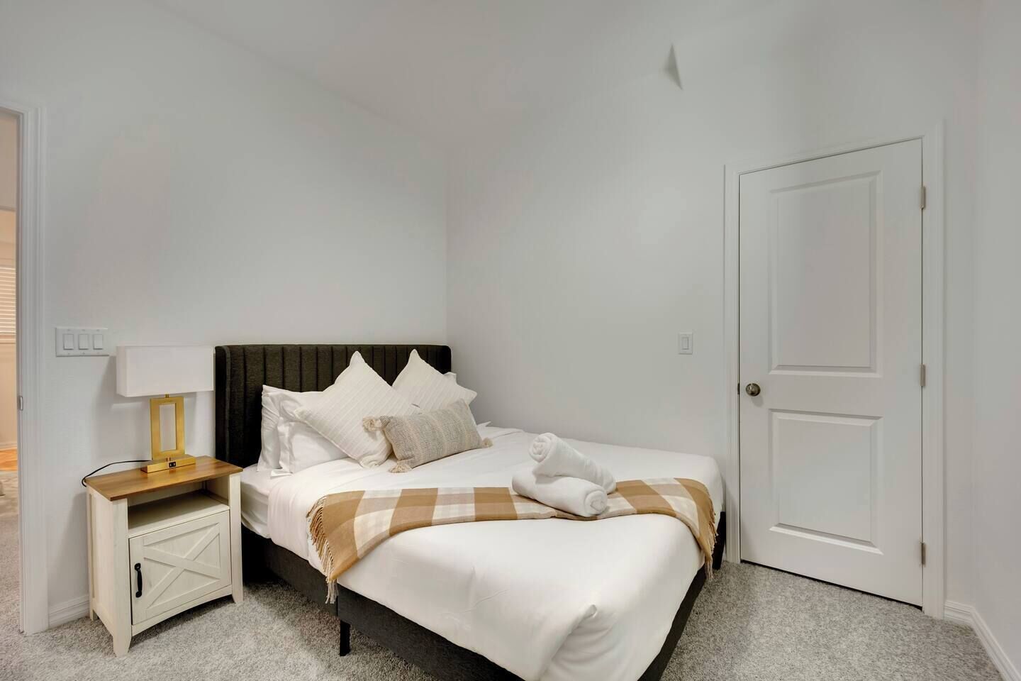A hotel room with a bed, a bedside table with a lamp, a wardrobe, and a door.