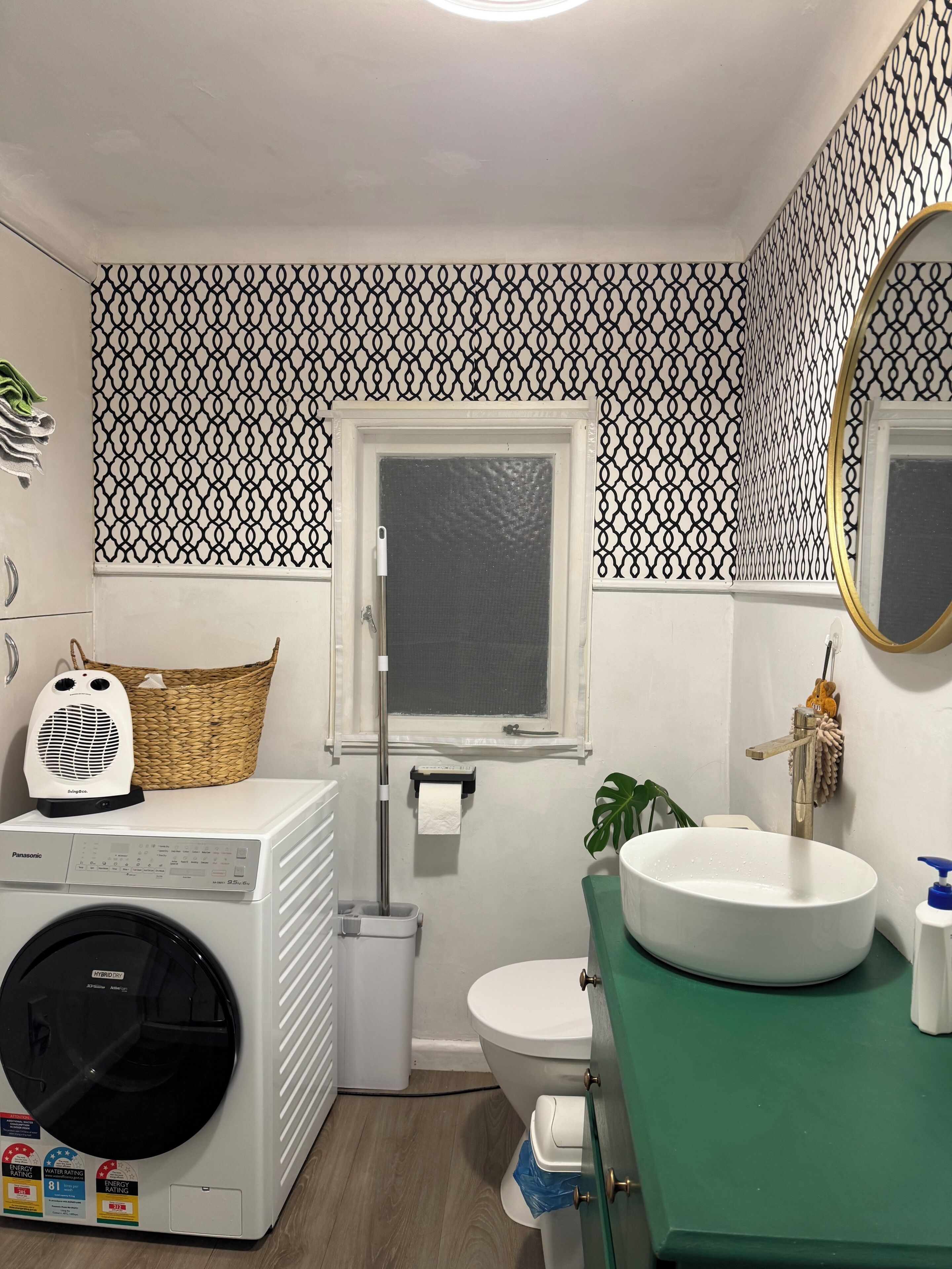 A bathroom with a washing machine, toilet, sink, and a window with a towel rack.