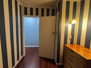A narrow hallway with striped walls, a wooden floor, and a door leading to another room. - Cosy beach retreat on Torbay. Enjoy a spacious room with entire house and garden (Torbay)