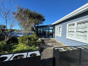 Il s’agit d’une propriété résidentielle dotée d’un patio couvert, d’un jardin avec différentes espèces de plantes et d’une maison à l’extérieur bleue et aux encadrements de fenêtres blancs.