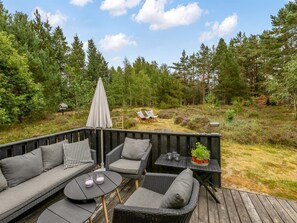 An outdoor seating area with a sofa, chairs, a table, and an umbrella.