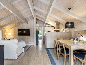 A spacious room with a large bed, a television, and a dining area with wooden furniture. - "Pia" - 685m from the sea by Interhome (Læsø)