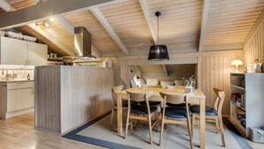 Ett modernt kök med träbjälkar, en köksö och en matplats med stolar och ett bord.
