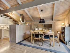 A modern kitchen with wooden beams, a central island, and a dining area with chairs and a table. - "Pia" - 685m from the sea by Interhome (Læsø)