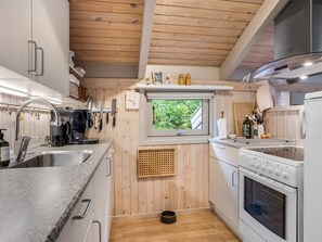 A compact kitchen with wooden walls, a window, and a built-in oven.