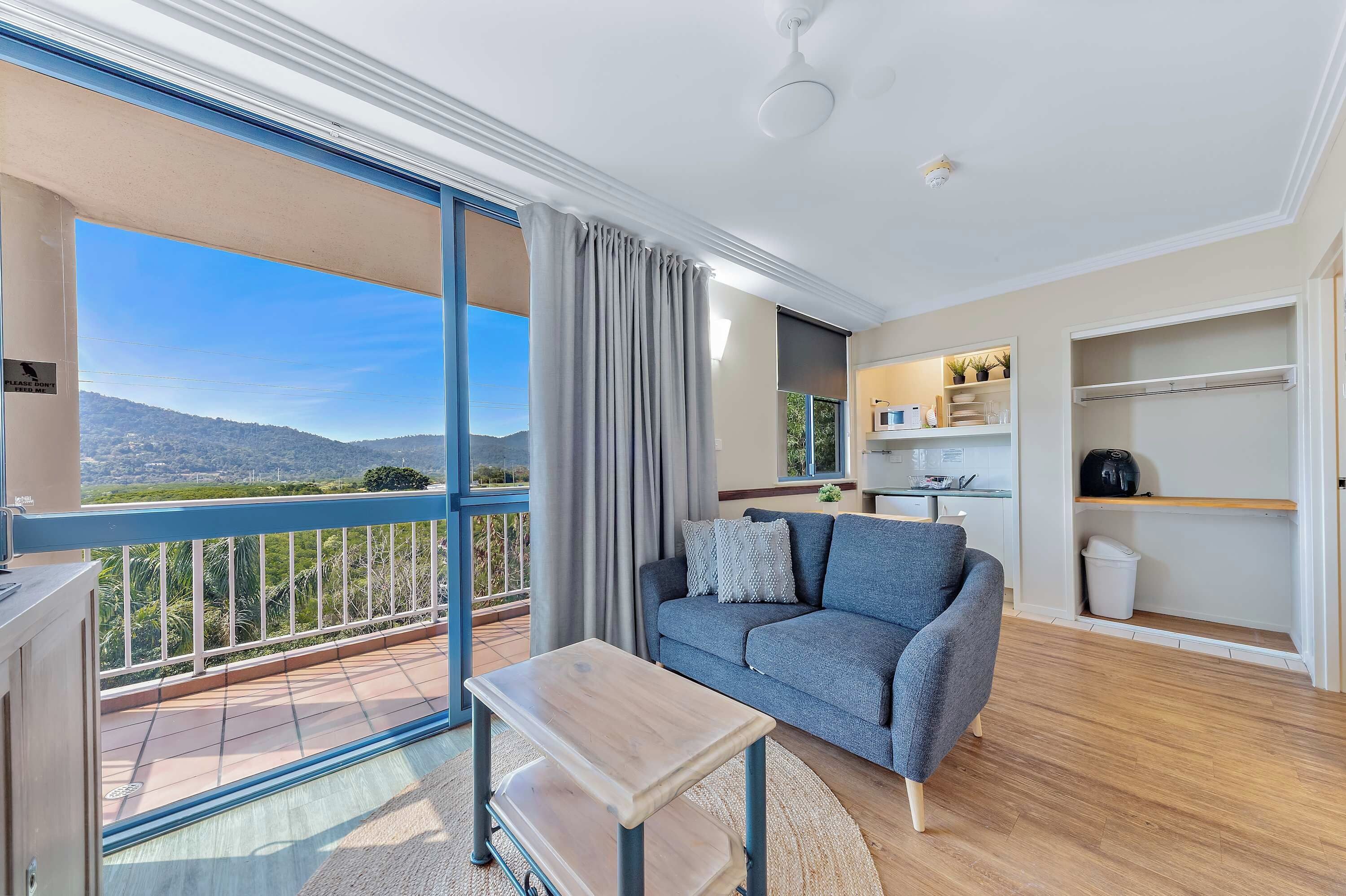 A modern living room with a sofa, a small table, and a view of a balcony with curtains.