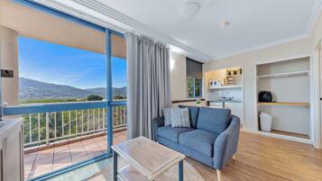 A modern living room with a sofa, a small table, and a view of a balcony with curtains.