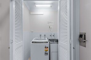 Un baño de hotel con una lavadora Whirlpool, un lavamanos y un inodoro.