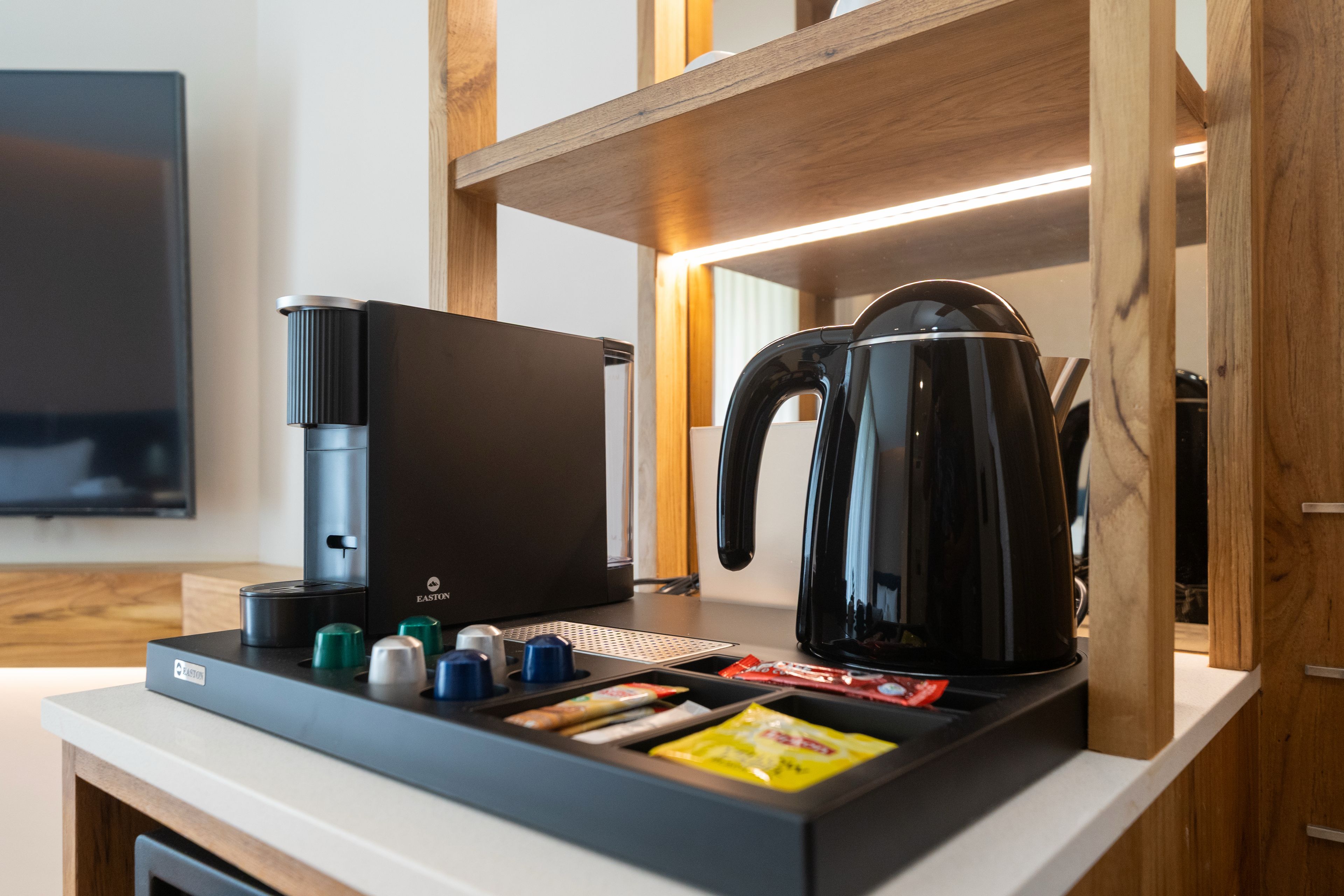 A kitchenette with a coffee maker, kettle, and condiment dispensers.