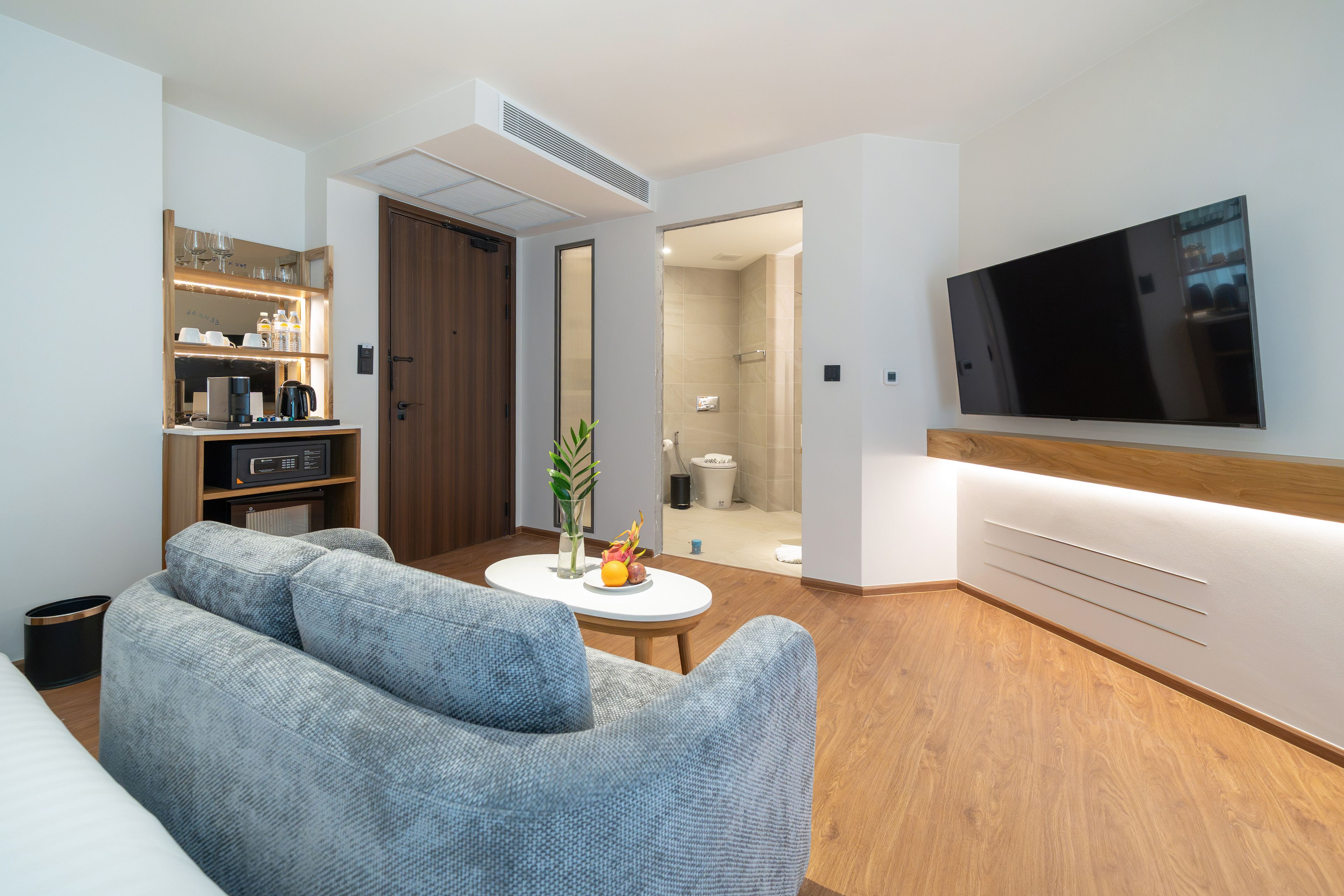 Una sala de estar moderna con un sofá, una mesa de centro y un televisor de pantalla plana montado en la pared.