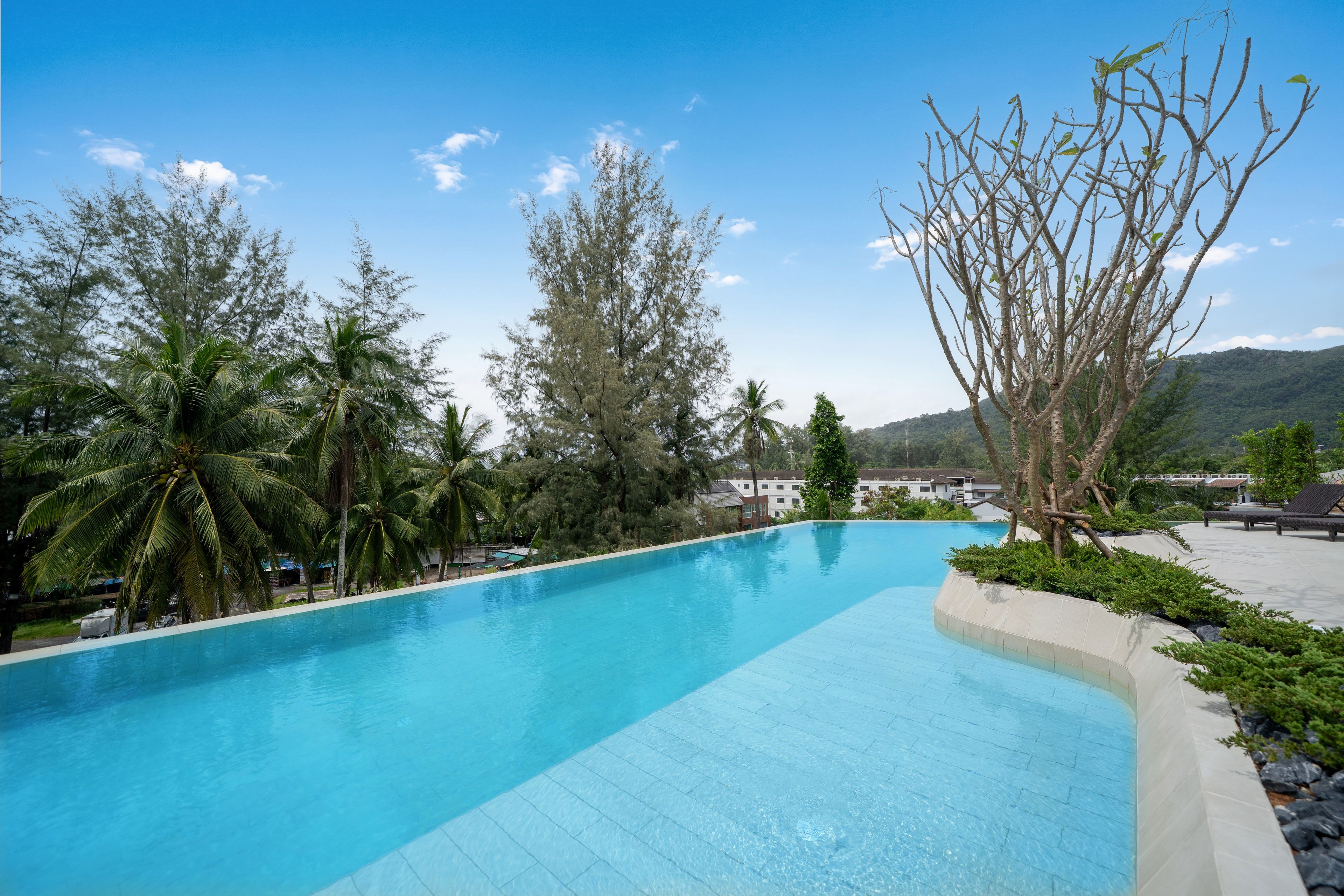 Piscina azul límpida rodeada por árvores e uma montanha ao fundo.