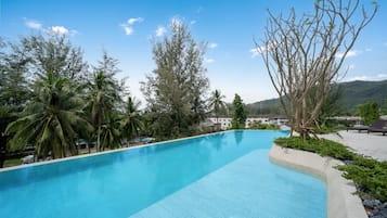 Piscina azul límpida rodeada por árvores e uma montanha ao fundo.