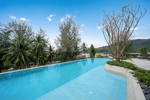 Piscina azul límpida rodeada por árvores e uma montanha ao fundo.